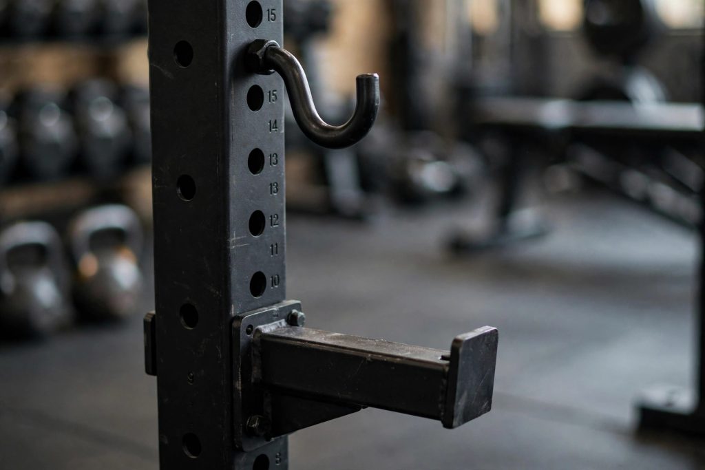 Close-up of J-hooks and safety spotter arms on a power rack upright